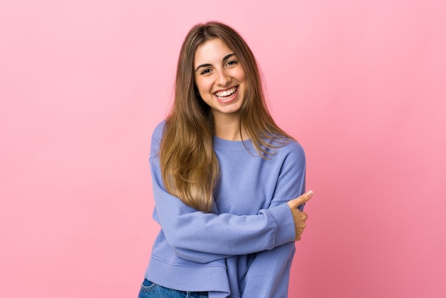 Jovem mulher sobre parede rosa isolada rindo