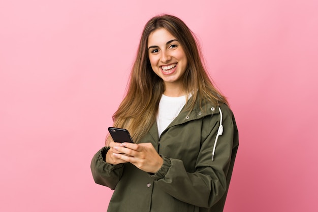 Jovem mulher sobre rosa isolado, enviando uma mensagem com o celular