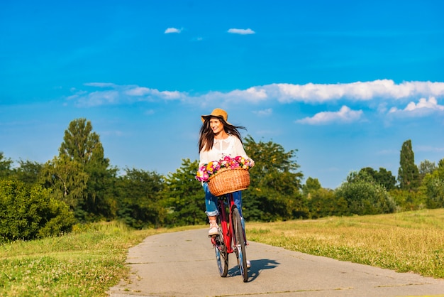 Jovem mulher sorridente anda de bicicleta em counrtyside