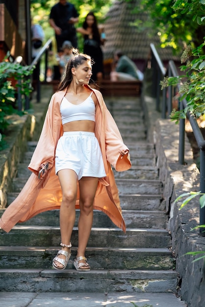 Jovem mulher sorridente andando no parque vestindo roupão