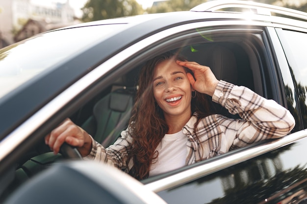 Jovem mulher sorridente dirigindo um carro na cidade