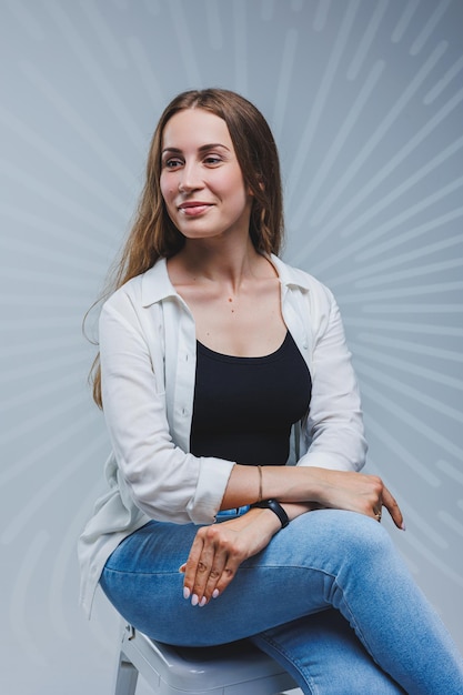 Jovem mulher sorridente em camiseta preta de camisa branca sobre fundo cinza Retrato de uma morena com um sorriso no rosto