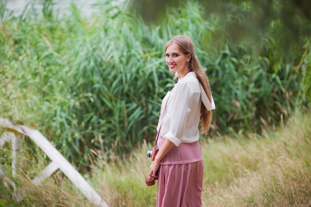 Jovem mulher sorridente em roupas de estilo vintage com câmera retro