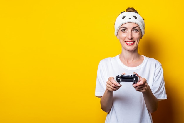 Jovem mulher sorridente, jogando um jogo virtual com um joystick nas mãos.