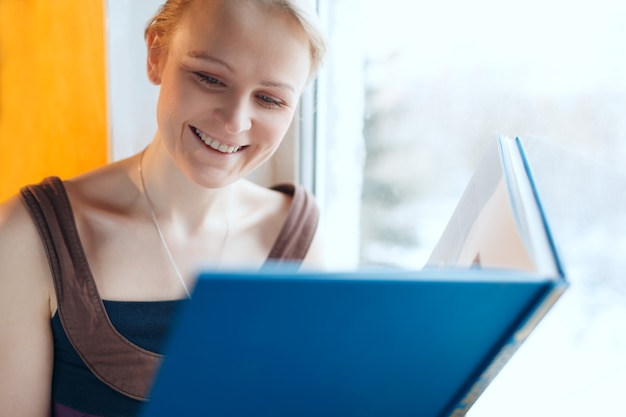 Jovem mulher sorridente, lendo um livro