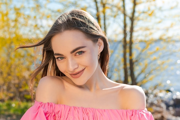 Jovem mulher sorridente muito estilosa se divertindo no cabelo comprido do parque da cidade