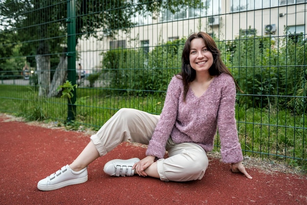 Jovem mulher sorridente posando no campo de esportes