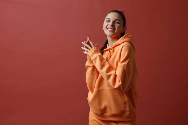 Jovem mulher sorridente positiva em roupas esportivas de fitness laranja dançando de pano