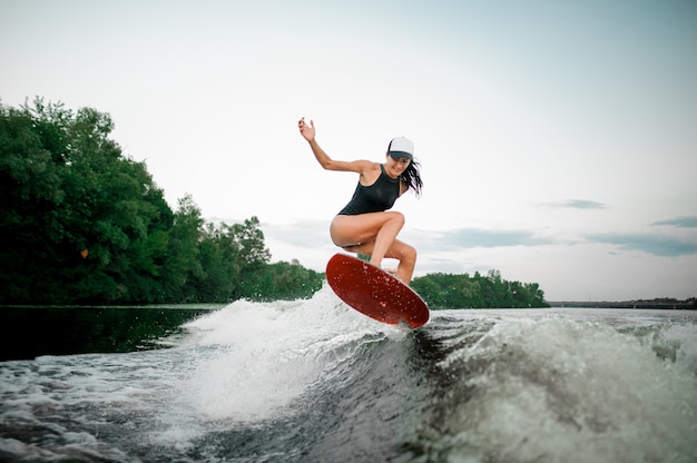 Jovem mulher sorridente pulando no wakesurf
