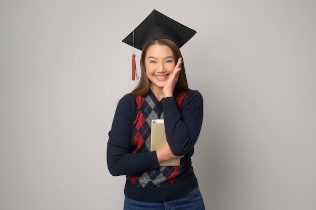 Jovem mulher sorridente segurando a educação de chapéu de formatura e a universidade conceptx9