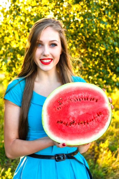 Jovem mulher sorridente segurando metade da melancia suculenta