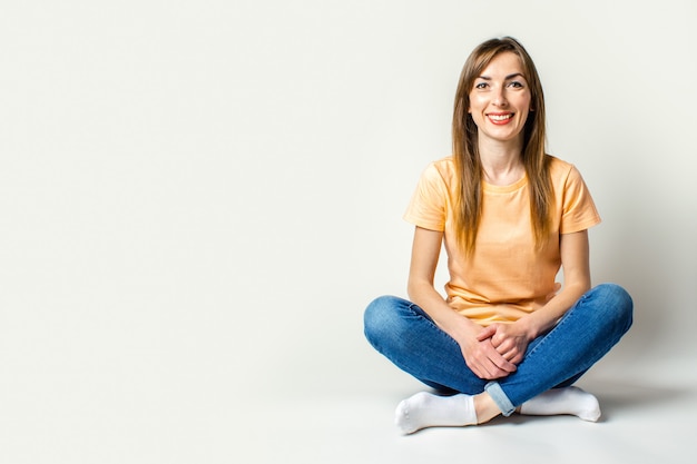 Jovem mulher sorridente, sentada no chão