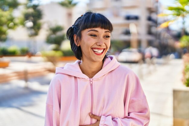 Jovem mulher sorrindo confiante em pé na rua