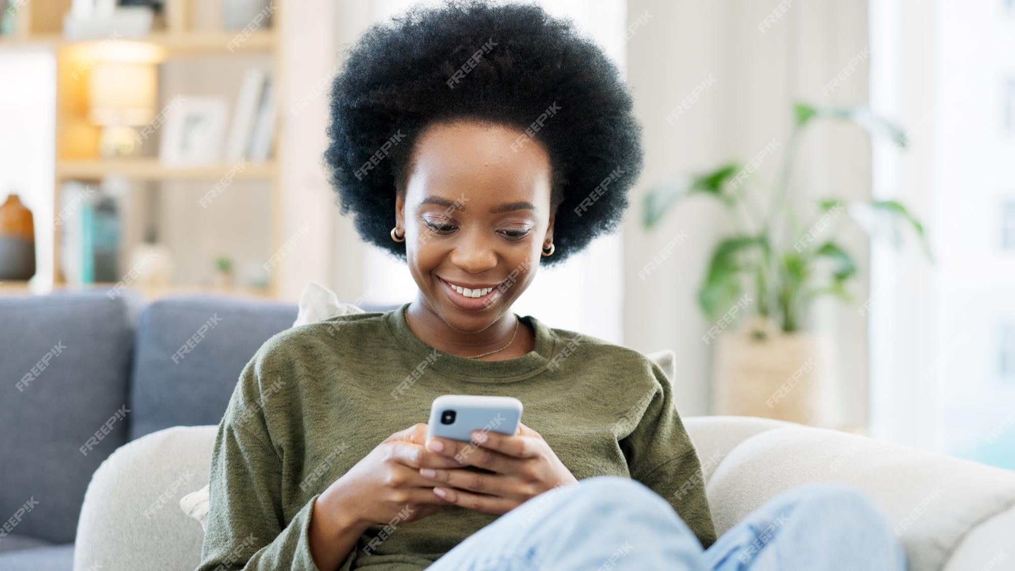 Jovem mulher sorrindo e rindo enquanto envia mensagens de texto em um  telefone em casa mulher alegre conversando com seus amigos com aplicativos  rolando mídias sociais e assistindo memes engraçados da internet enquanto  relaxa em um sofá