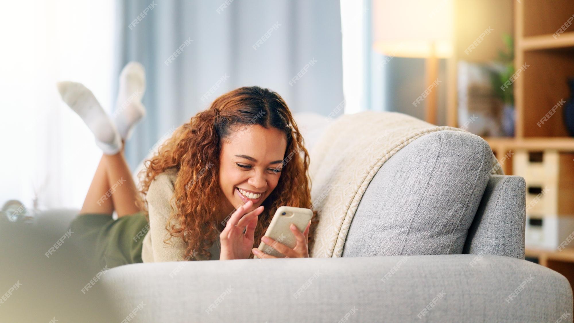 Jovem mulher sorrindo e rindo enquanto enviava mensagens de texto em um  telefone em casa mulher alegre conversando com seus amigos nas mídias  sociais navegando online e assistindo memes engraçados da internet