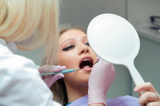 Jovem mulher tendo check-up médico no consultório do dentista pelo médico.