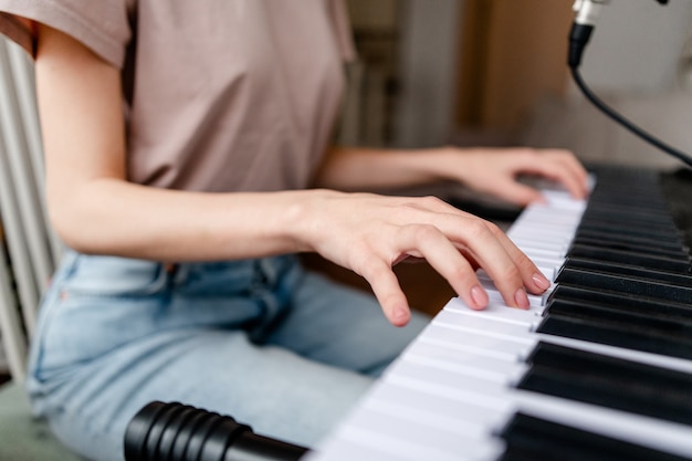 Jovem mulher tocando piano em casa. closeup de mãos