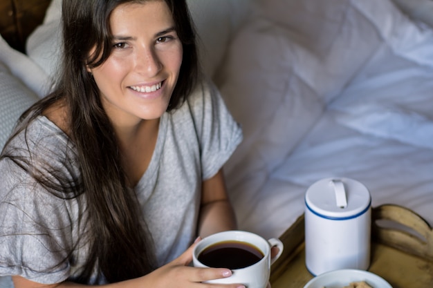 Jovem mulher tomando café da manhã na cama