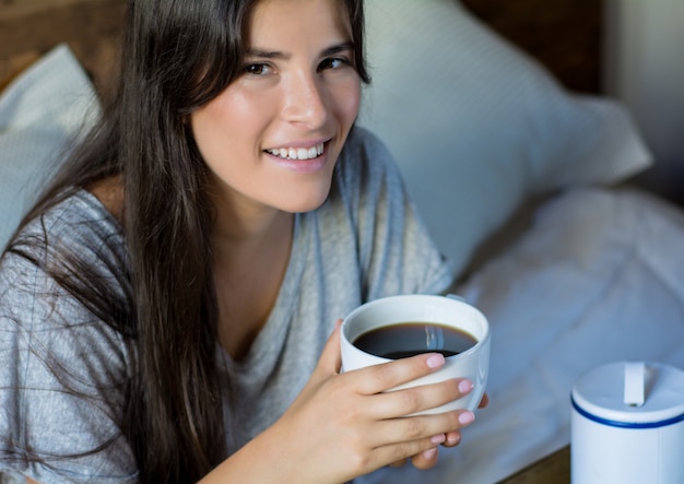 Jovem mulher tomando café da manhã na cama