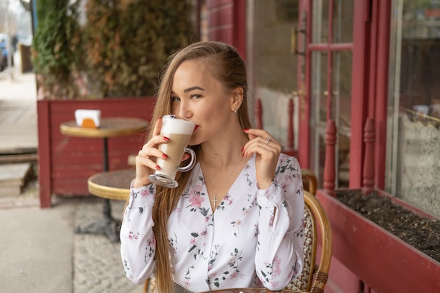 Jovem mulher tomando café em um café de rua parisiense