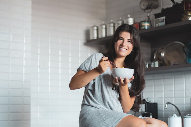 Jovem mulher tomando café na cozinha