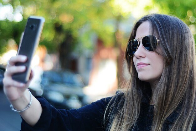 Jovem mulher tomando selfie com seu smartphone.