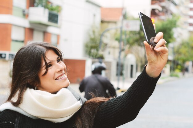 Jovem mulher tomando selfie com seu smartphone.