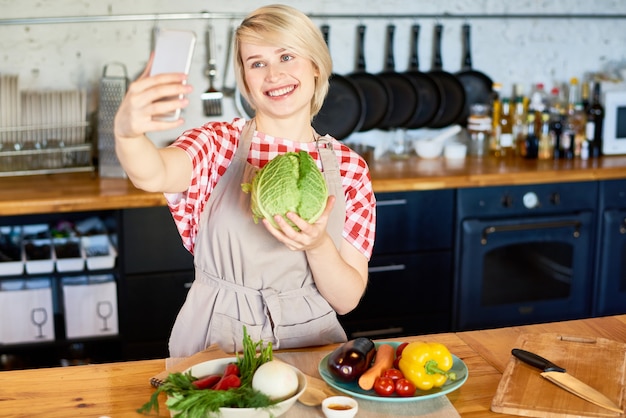 Jovem mulher tomando Selfie na cozinha