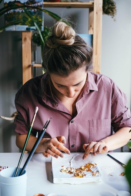 Foto jovem mulher trabalhando com folha de ouro e relevo de gesso