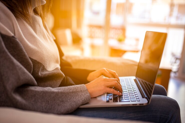 Jovem mulher trabalhando em um laptop sentada em casa ao pôr do sol