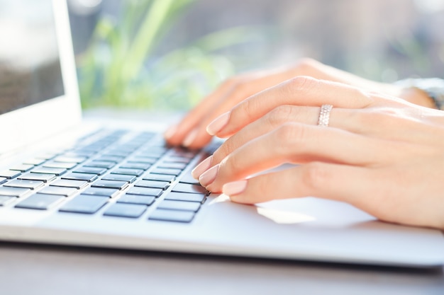 Jovem mulher trabalhando no laptop no café no dia ensolarado