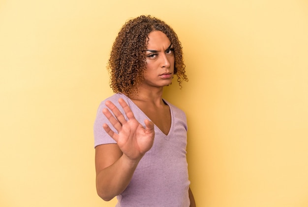 Jovem mulher transexual latina isolada em fundo amarelo, rejeitando alguém mostrando um gesto de nojo.