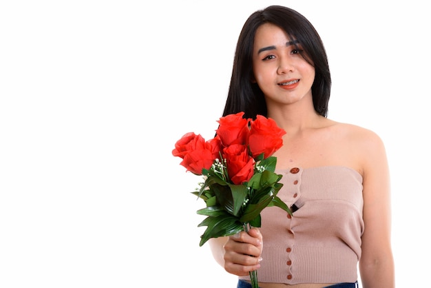 jovem mulher transgênero asiática feliz sorrindo enquanto segura rosas