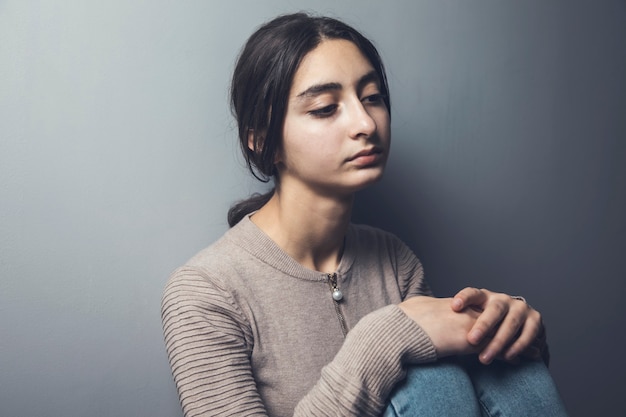 Jovem mulher triste sentada no chão