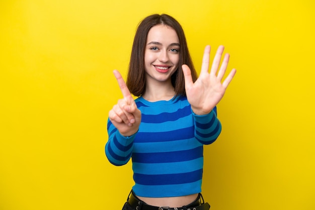 Jovem mulher ucraniana isolada em fundo amarelo contando seis com os dedos