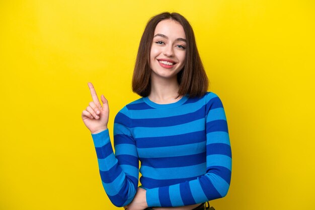 Jovem mulher ucraniana isolada em fundo amarelo mostrando e levantando um dedo em sinal do melhor