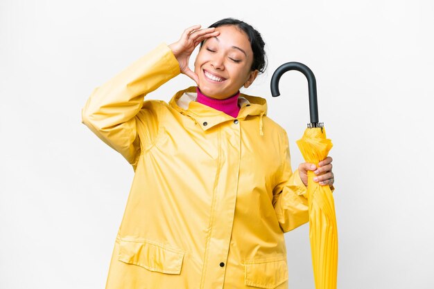 Jovem mulher uruguaia com casaco à prova de chuva e guarda-chuva sobre fundo branco isolado sorrindo muito