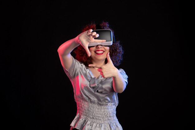 Jovem mulher usando fone de ouvido de realidade virtual em superfície escura