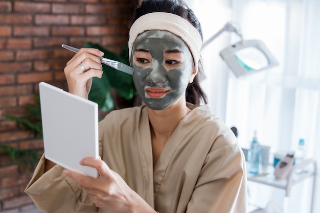 Jovem mulher usando lama de máscara facial