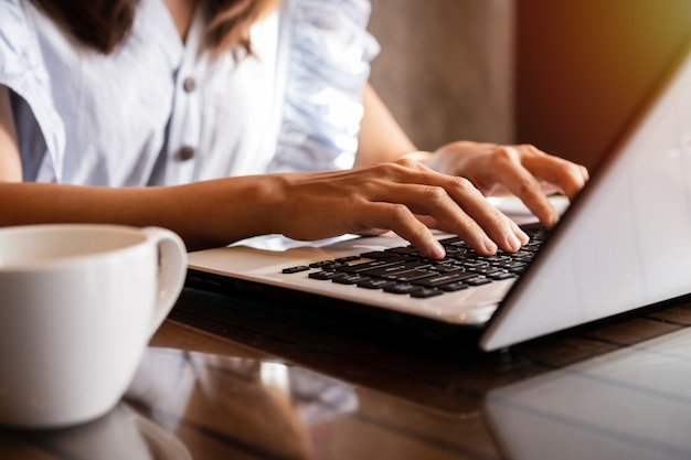 Jovem mulher usando laptop com uma xícara de café no café