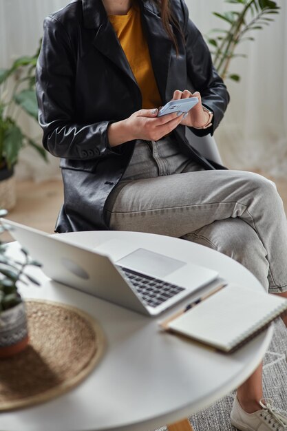 Jovem mulher usando laptop e celular sentado no local de trabalho em casa trabalho remoto