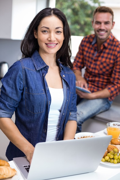 Jovem mulher usando laptop e homem usando tablet digital