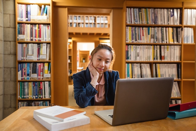 Jovem mulher usando laptop na biblioteca