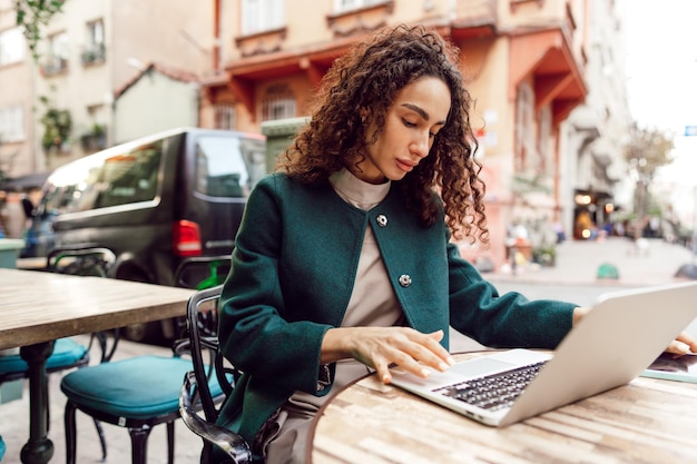 Jovem mulher usando laptop no café ao ar livre