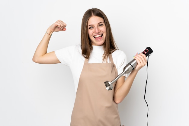 Jovem mulher usando o liquidificador isolado no branco fazendo forte gesto