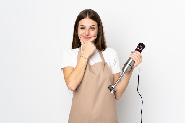 Jovem mulher usando o liquidificador na parede branca rindo