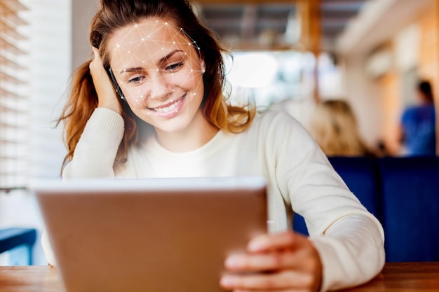 Jovem mulher usando reconhecimento facial via telefone celular inteligente dentro de casa, verificação biométrica