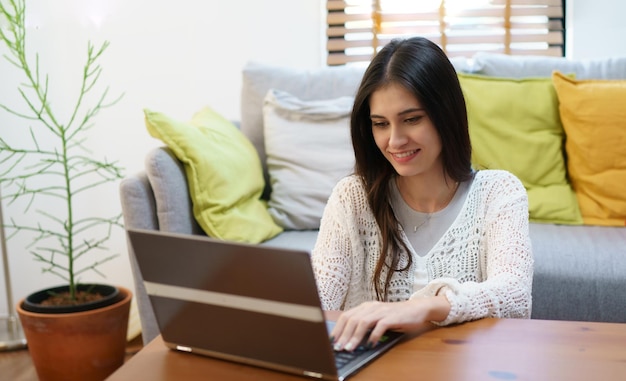 Jovem mulher usando seu laptop em casa