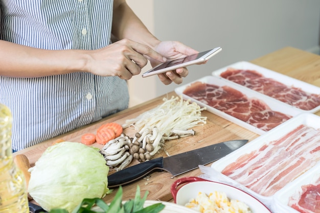 Jovem mulher usando seu smartphone na cozinha