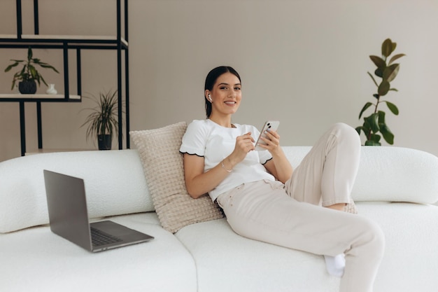 Jovem mulher usando seus gadgets e relaxando em casa